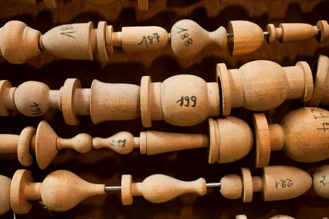 Moules en bois destinés à être satinés ou roulés de soie pour former une partie du gland d'une embrasse. Chaque élément est habillé à la main par une ouvreuse, qui, à partir des agréments préparés un à un à l'atelier, organise le décor.