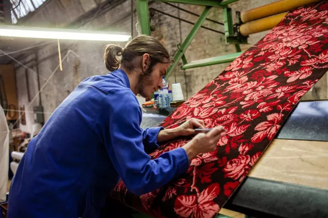 Chaque pièce de moquette à motifs floraux est contrôlée et les éventuels défauts de tissage ou de tonte repris.