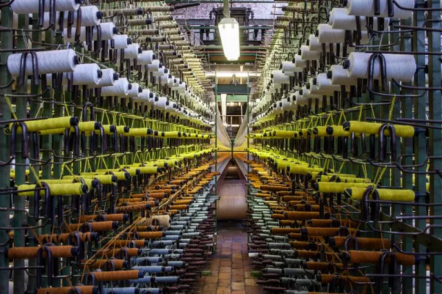 A l'arrière du métier à tisser la moquette, le cantre rassemble toutes les bobines de laine nécessaires au tissage ;